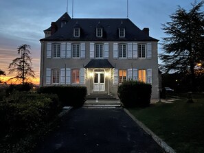 A two-story building with a symmetrical facade, a central entrance with a door, and a driveway leading to the entrance.