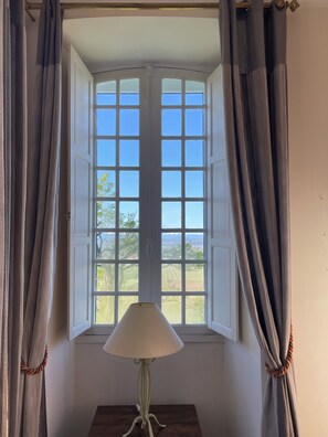 Une pièce avec une fenêtre, des rideaux et une lampe.