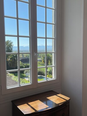 Ein Zimmer mit großem Fenster und Blick auf eine Berglandschaft sowie ein Schwimmbad.