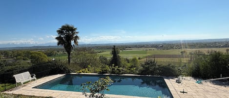 Une piscine offrant une vue sur les montagnes et les champs environnants.
