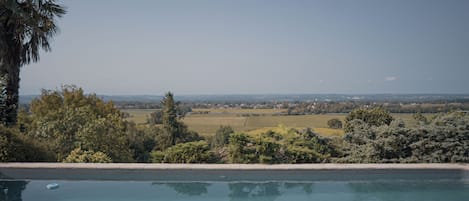 Una piscina con vista su un paesaggio rurale, campi e edifici in lontananza.