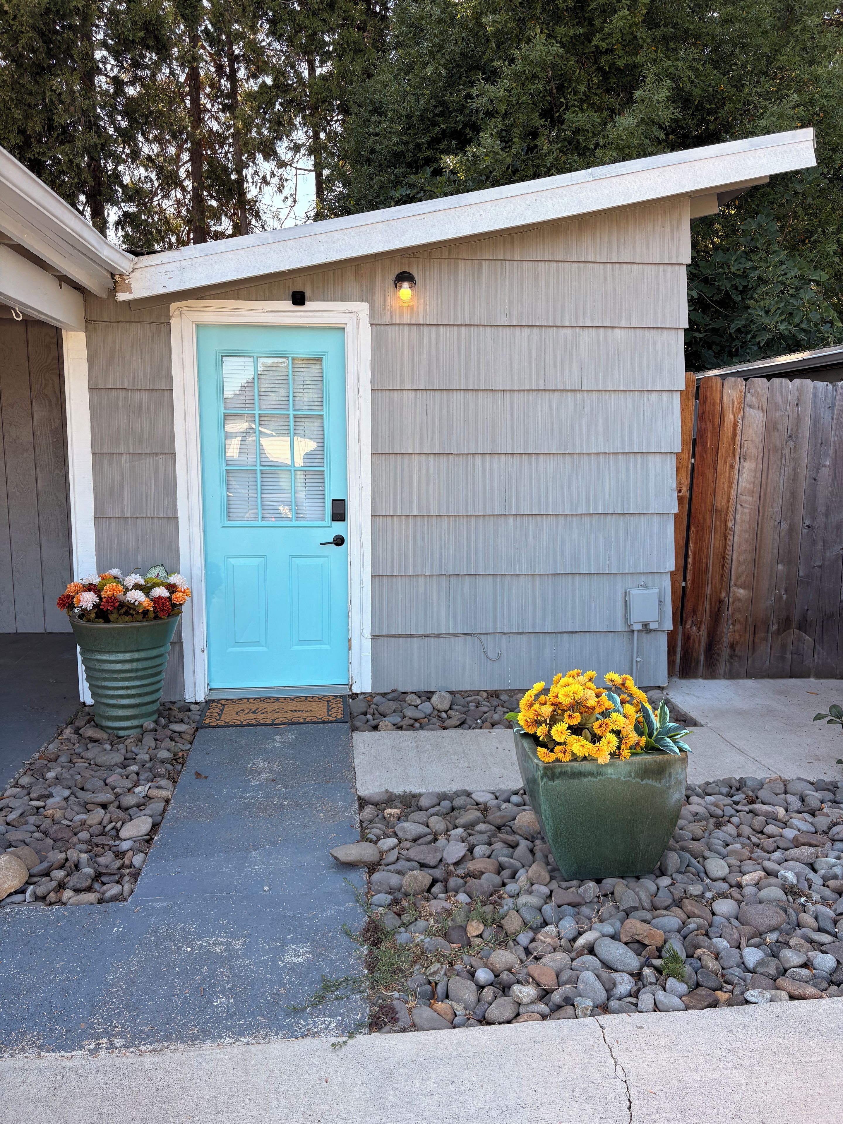 A house with a blue door, a small porch, and two flower pots.