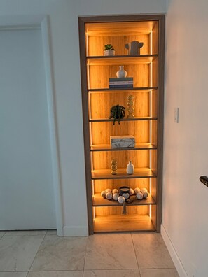 Una estantería de madera con varios estantes, algunos con objetos decorativos y otros con libros.