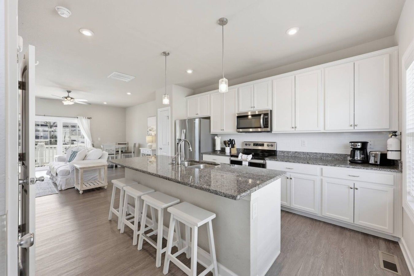 A modern kitchen with white cabinets, a granite countertop, and stainless steel appliances.