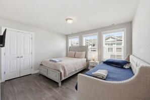 A bedroom with a double bed, a bedside table with a lamp, a wardrobe, and a window with blinds. - New 4BR | 1 blck to Atlantic Park | 2 blcks Beach (Virginia Beach)