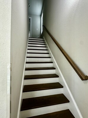 A staircase with white walls and dark wooden steps. - Brand New 4BR | 2 Blks to Beach & Atlantic Park (Virginia Beach)