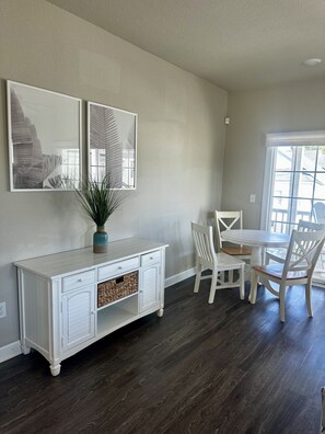 A dining area with a white table and chairs, a white cabinet with drawers, and two framed artworks on the wall. - Coastal 3BR | 2 Blks to Beach & Atlantic Park (Virginia Beach)