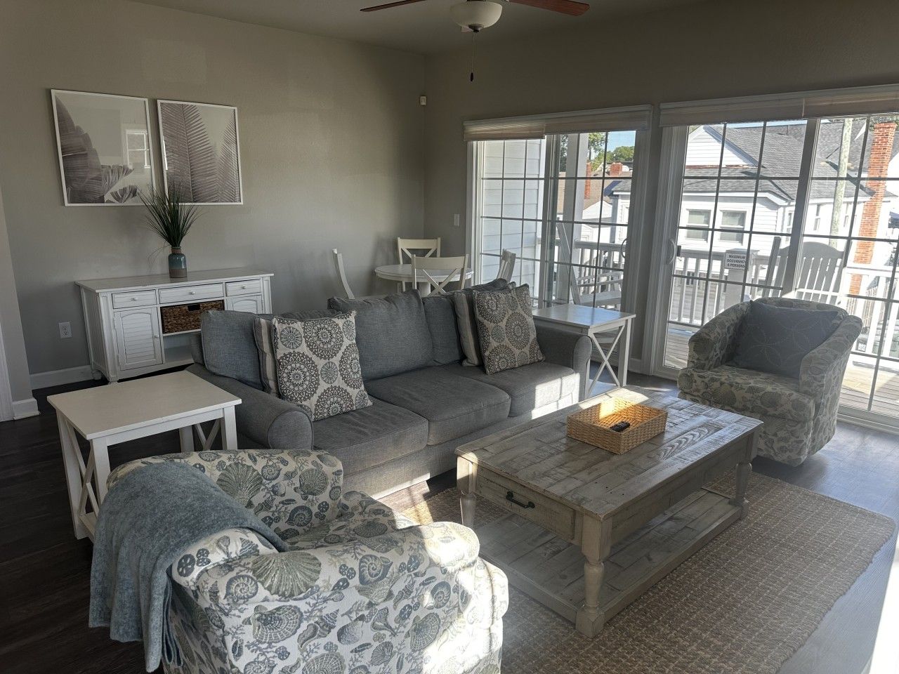 A living room with a grey sofa, patterned armchairs, a coffee table, and a white side table.