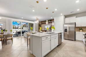 A modern kitchen with a central island, stainless steel appliances, and pendant lighting. - Brand New   Modern 5BR with Pool   Game Room 16212 (Clermont)