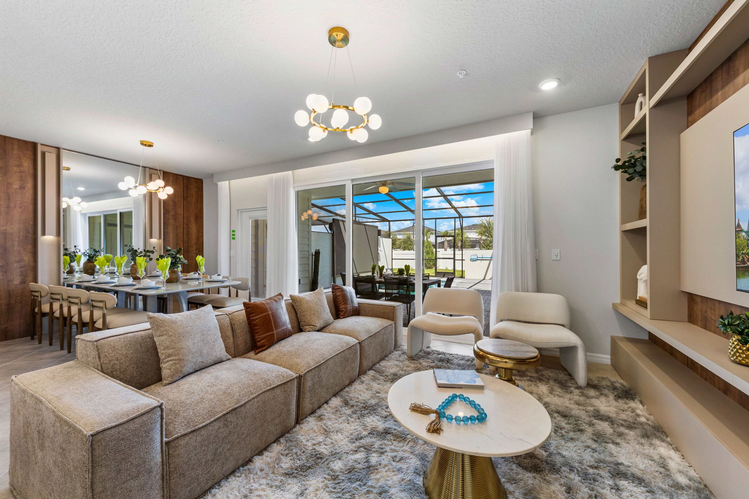 A modern living room with a sectional sofa, a round coffee table, and a dining area with a glass-enclosed patio.