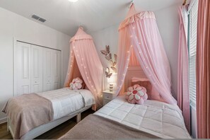 A bedroom with two beds, each with a canopy, a nightstand, a lamp, and a decorative butterfly wall piece. - Brand New   Family 6BR Pool Spa   Game Lounge 7875 (Kissimmee)