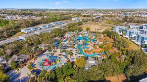 An aerial view of a resort with a large pool area, multiple buildings, and surrounding greenery. - Brand New   Family 6BR Pool Spa   Game Lounge 7875 (Kissimmee)