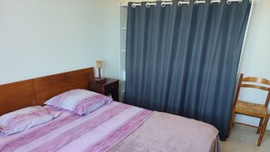 Uma cama com um cobertor listrado, uma mesa de cabeceira com abajur e uma cadeira.