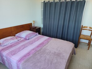 Un lit avec une couverture à rayures, une table de chevet avec une lampe et une chaise.
