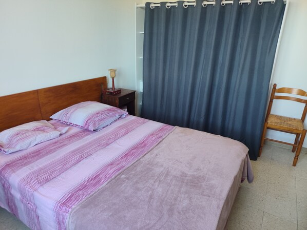 A bed with a striped blanket, a bedside table with a lamp, and a chair.