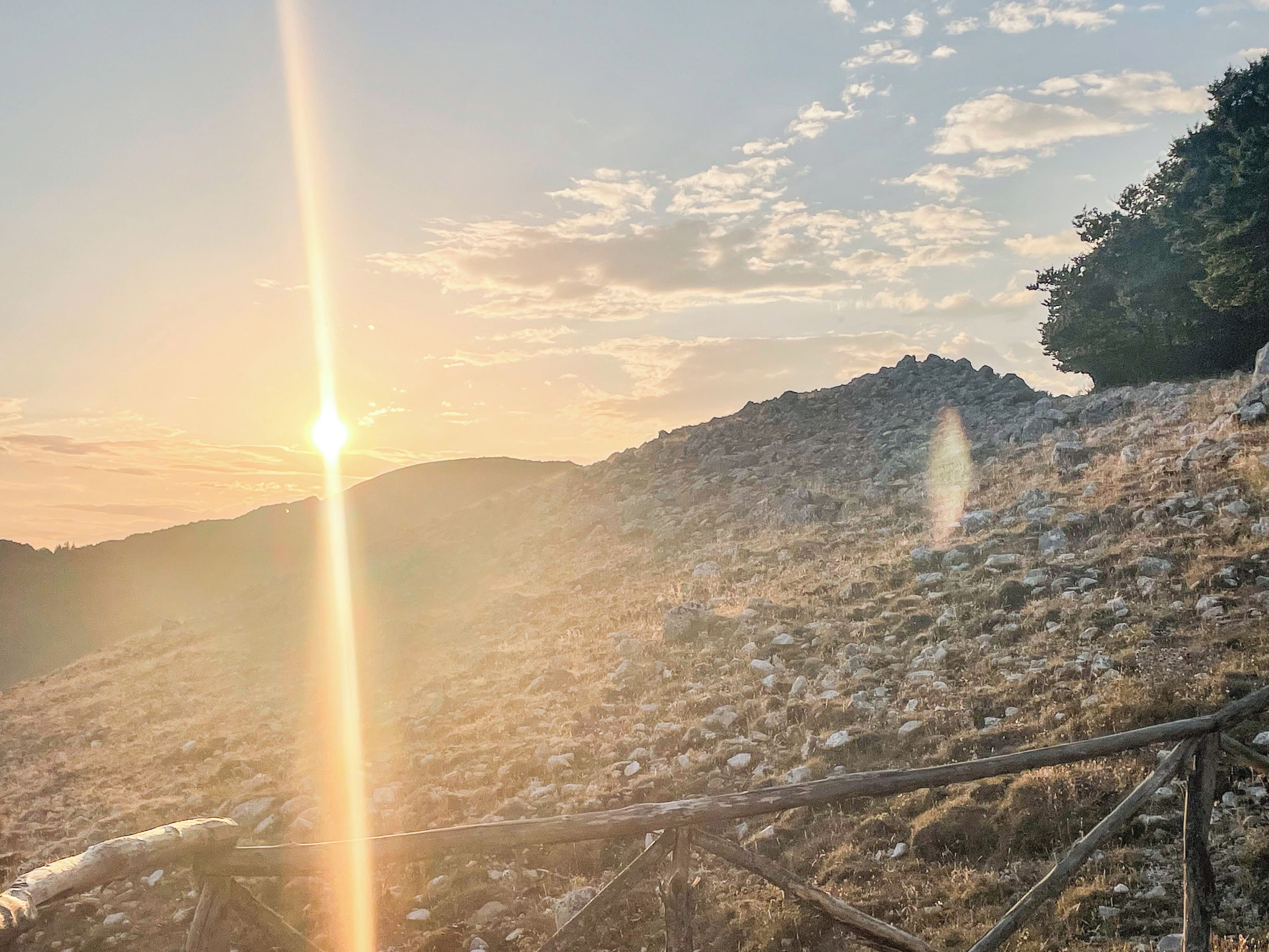 A mountainous landscape with a sun setting in the background.