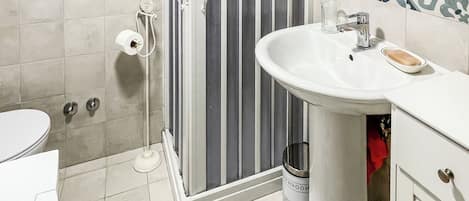 Un baño con ducha, inodoro, lavabo y espejo.