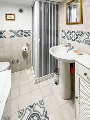 A bathroom with a shower, toilet, sink, and a mirror. - Il Mandorlo di Pierina (Vitulano)