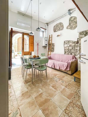 A dining area with a table and chairs, a pink sofa, and a stone wall. - Il Mandorlo di Pierina (Vitulano)