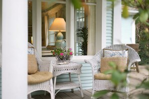 A porch with wicker chairs, a small table with a potted plant, and a lamp. - Lakeside Charmer Steps To Association Beach! (Lakeside)