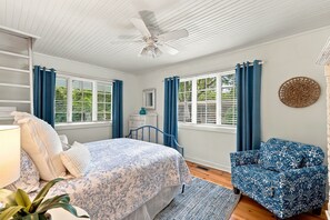 A bedroom with a bed, a chair, a ceiling fan, and windows with curtains. - Lakeside Charmer Steps To Association Beach! (Lakeside)