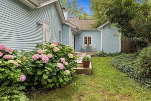 A house with a blue exterior, a small porch with two chairs, and a potted plant. - Lakeside Charmer Steps To Association Beach! (Lakeside)