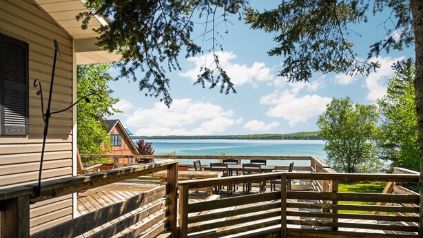 Une terrasse en bois, agréée de mobilier d’extérieur, donnant sur un lac.