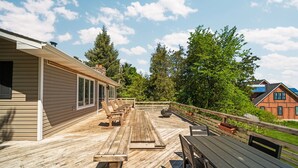 Une terrasse en bois avec des sièges d’extérieur et une cheminée en pierre.