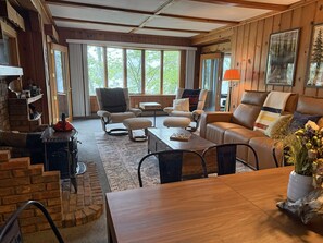 A cozy living room with a fireplace, comfortable seating, and large windows.