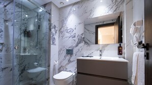 A modern bathroom with a glass-enclosed shower, a toilet, and a vanity with a mirror.