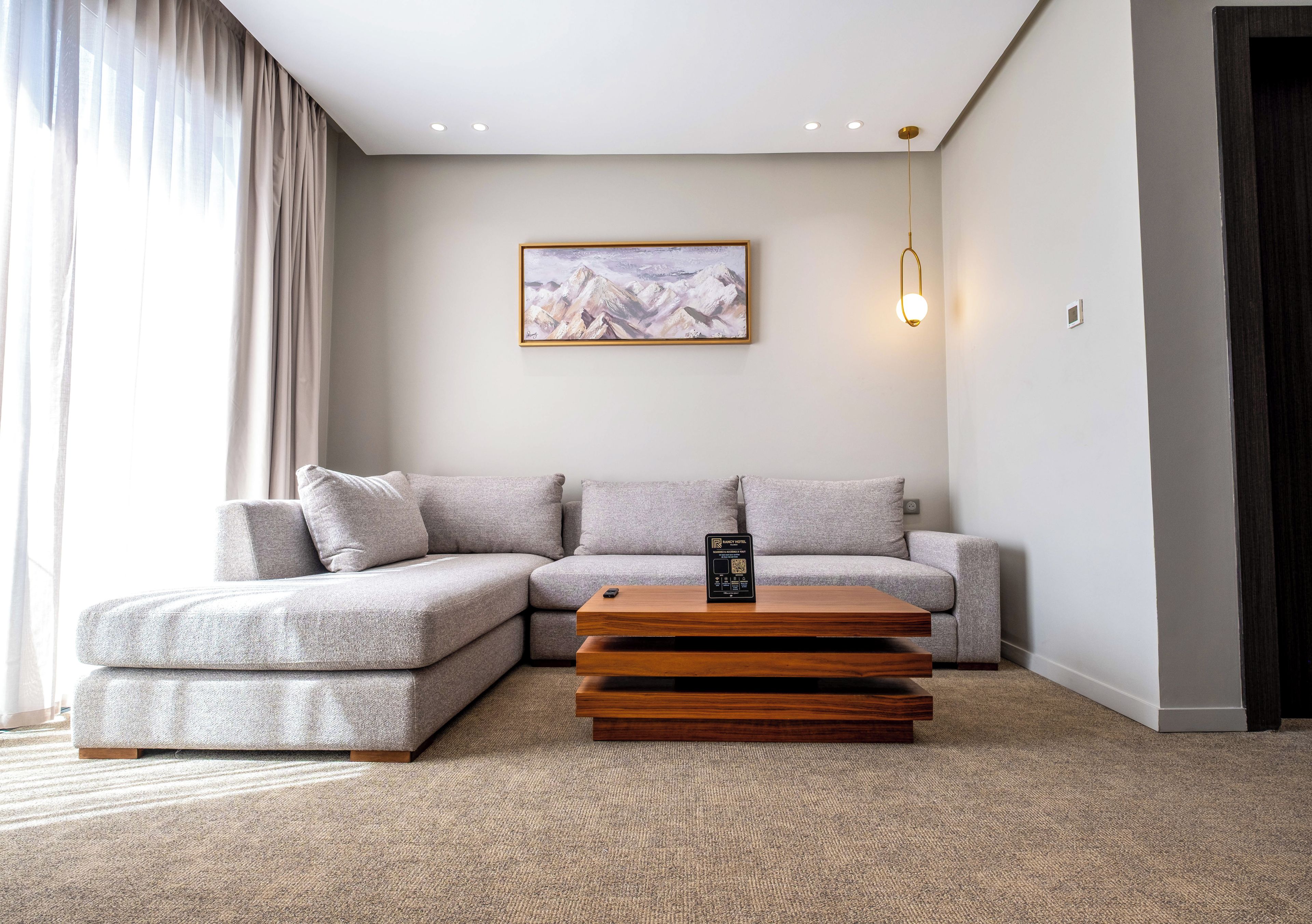 A modern living room with a sectional sofa, a wooden coffee table, and a painting on the wall.