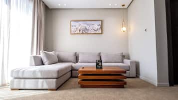 A modern living room with a sectional sofa, a wooden coffee table, and a painting on the wall.