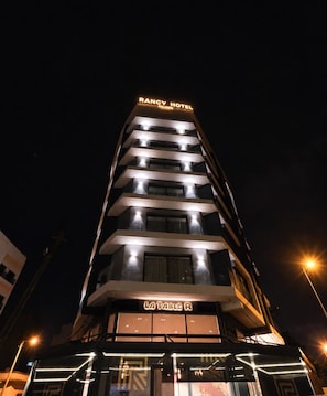 A multi-story hotel with illuminated signage for 'RANCY HOTEL PALMER' and 'LA TABLE R' at the ground level. - Rancy Hotel Palmier (Casablanca)
