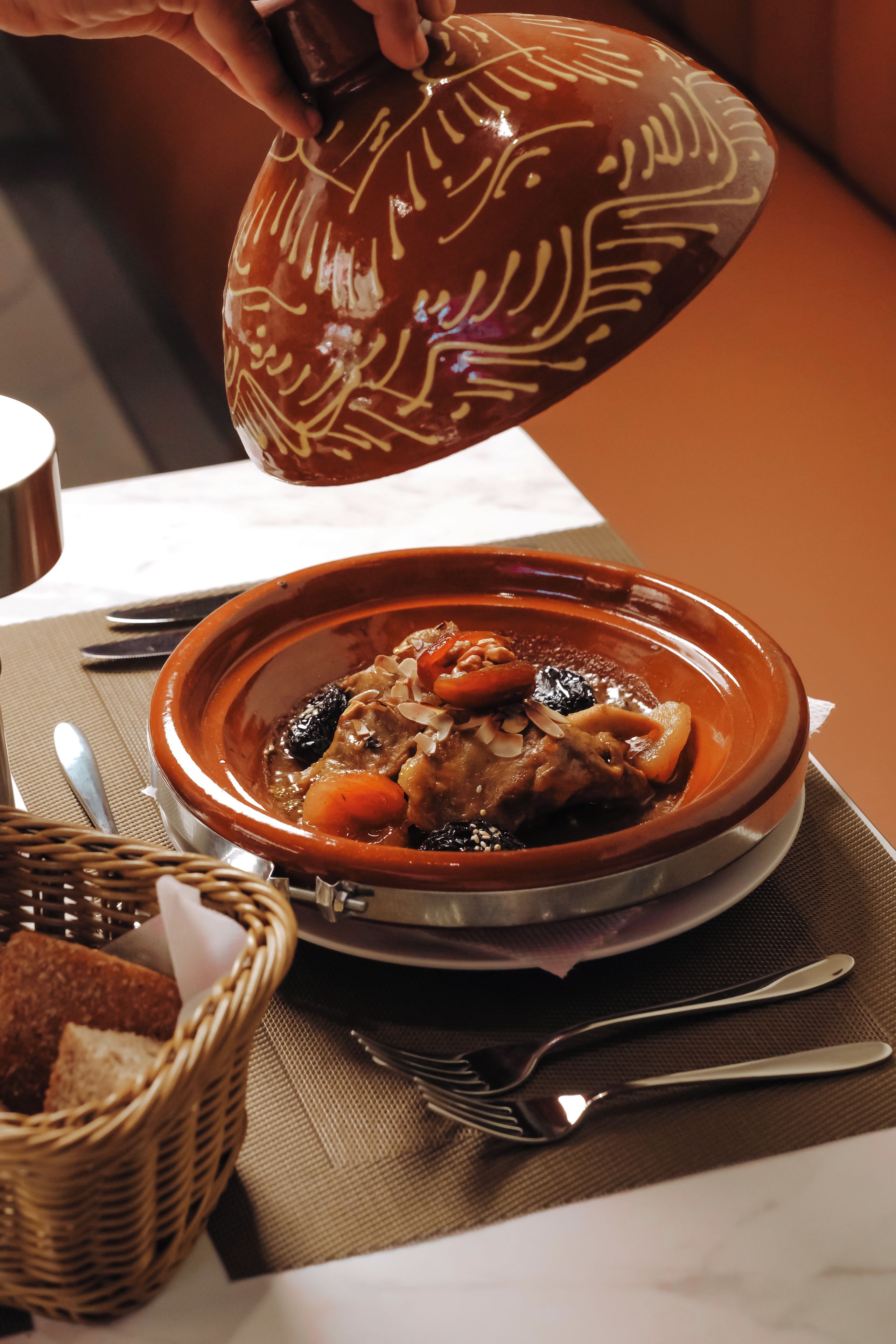 A traditional clay pot filled with stew, placed on a woven mat.