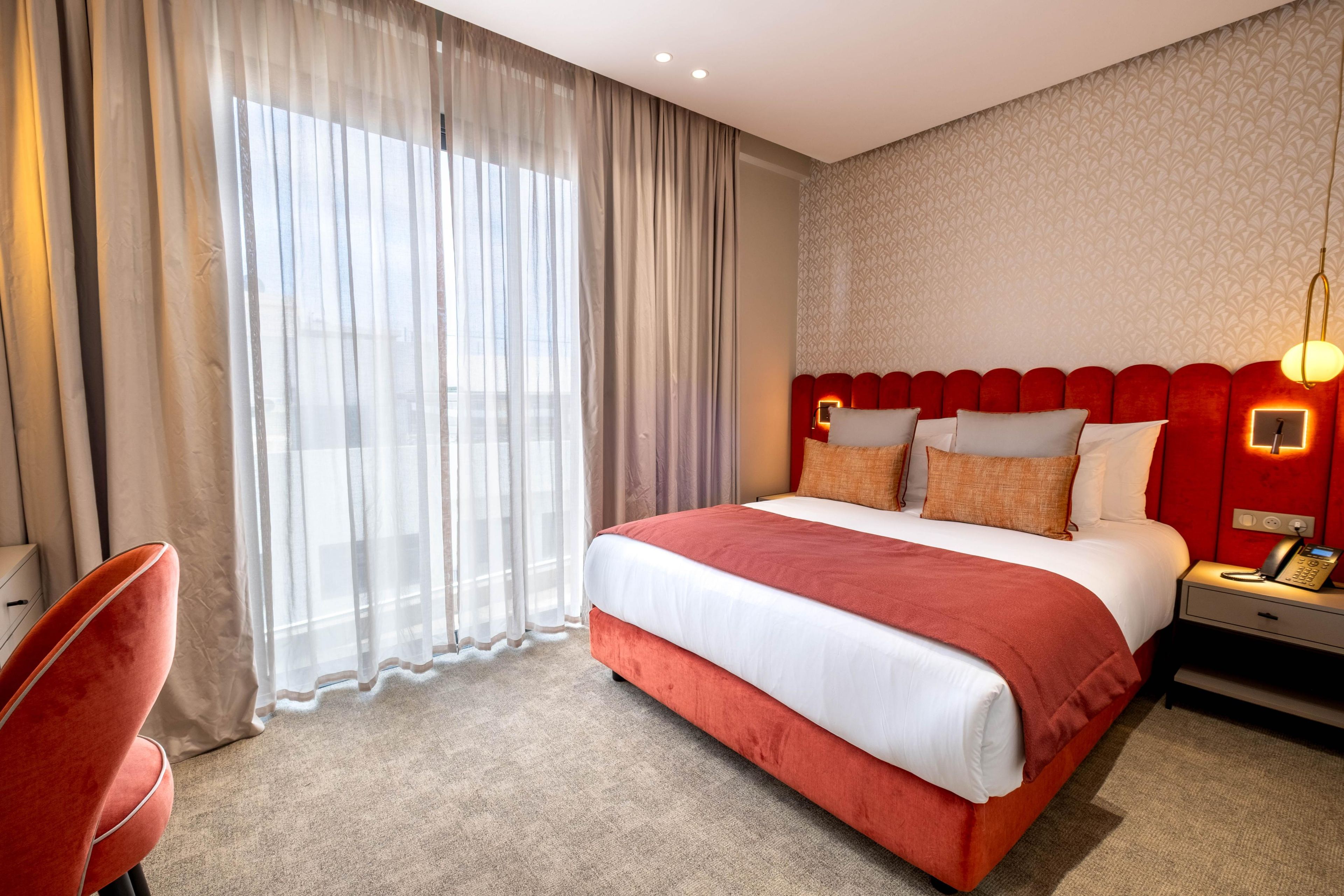 Una habitación de hotel con una cama grande, un escritorio con teléfono y una silla.