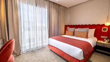 Una habitación de hotel con una cama grande, un escritorio con teléfono y una silla.