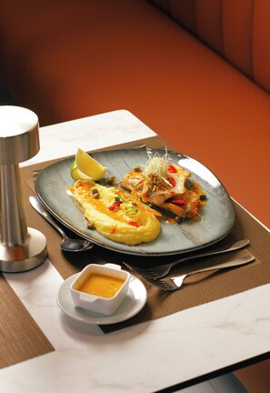 A plate of food with a side of sauce and a small bowl of sauce on a table.
