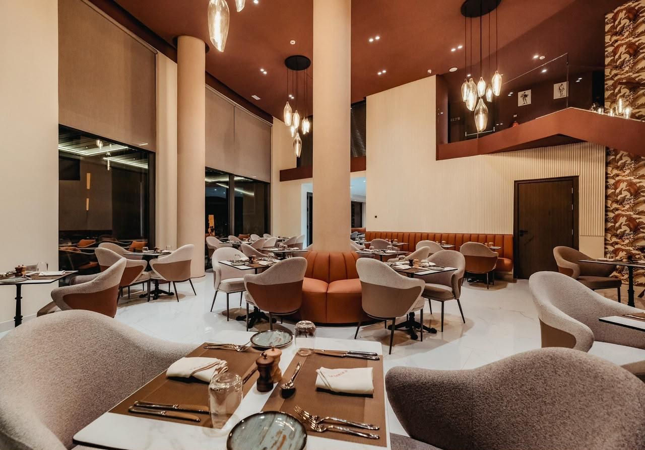 Un restaurant espaiós amb sostres alts, diverses taules i lluminàries modernes.