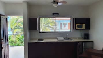 A compact kitchen with a window, a ceiling fan, and a microwave.