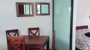 A dining area with a wooden table and chairs, two wall-mounted mirrors, and a sliding glass door leading to a bedroom. - Marina Loft Unit 224,2 Floor (Sardinal)
