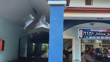 A building with a blue and white facade, a visible entrance, and a sign for a barber shop.