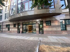 Un edificio moderno con una entrada curva, ventanas amplias y un área pavimentada.