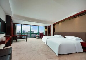A hotel room with a large bed, a desk, a chair, and a TV. There is a view of the city through large windows. - Chongqing Empark Grand Hotel (Chongqing)