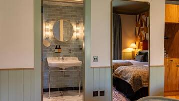 A bathroom with a sink, mirror, and a view into a bedroom with a bed and nightstand.