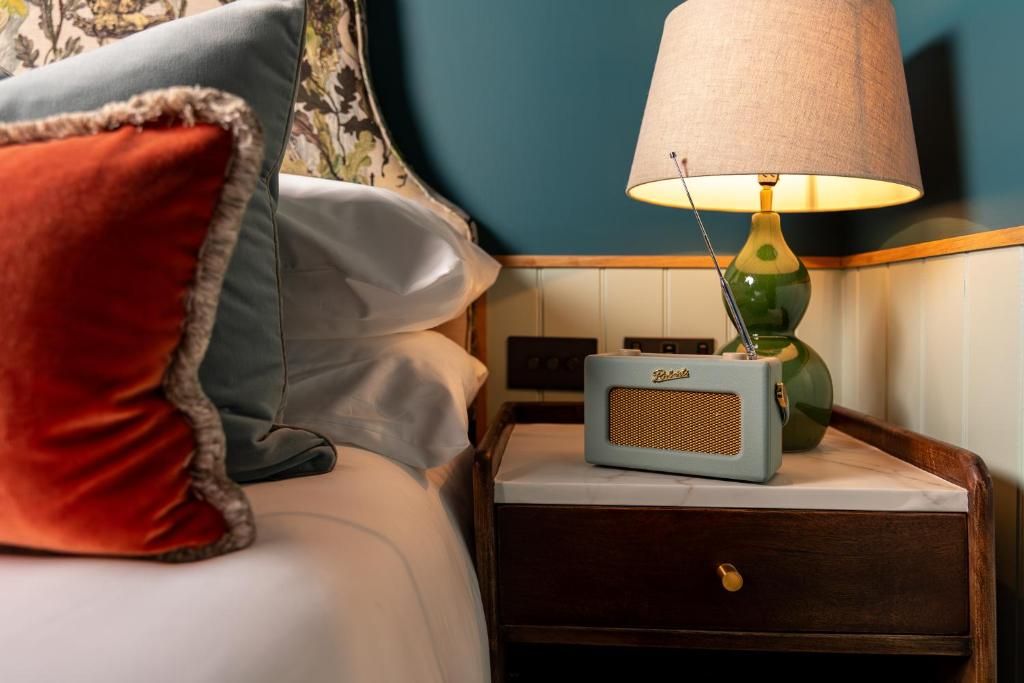 Una cama con almohadas, una mesita de noche con una lámpara y un radio.