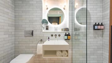 Un baño moderno con inodoro, lavabo con espejo y cabina de ducha de vidrio.
