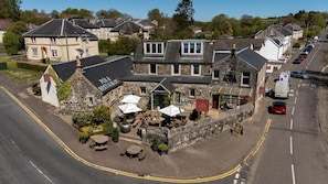 A stone building with a restaurant sign, outdoor seating, and a street view.
