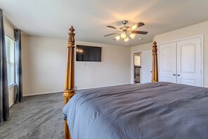 A bedroom with a four-poster bed, a ceiling fan, and a flat-screen TV mounted on the wall. - Spacious 4BR Richmond Home w/ Game & Media Room (Richmond)