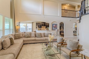 A spacious living room with a large sectional sofa, a glass coffee table, and a dining area with a marble table. - Spacious 4BR Richmond Home w/ Game & Media Room (Richmond)