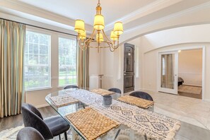 A dining area with a glass table, chairs, a chandelier, and a patterned rug. - Spacious 4BR Richmond Home w/ Game & Media Room (Richmond)